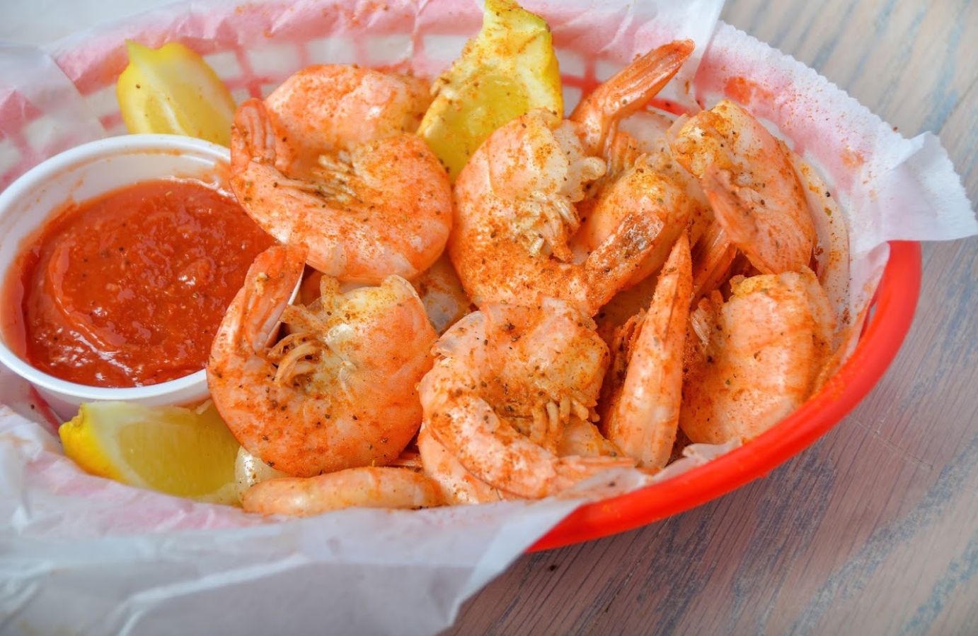 Closeup of a bowl of shrimp with lemons and dipping sauce on the side