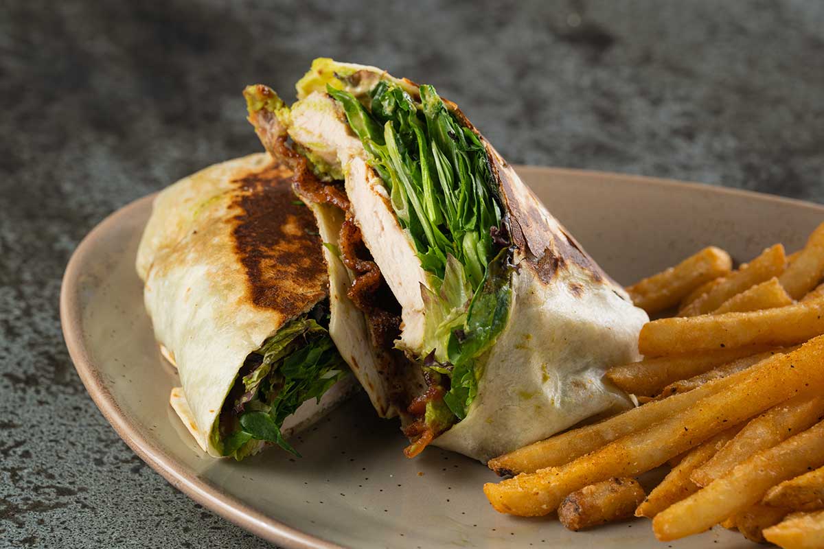 Chicken wrap, with avocado, bacon, lettuce and fries on the side