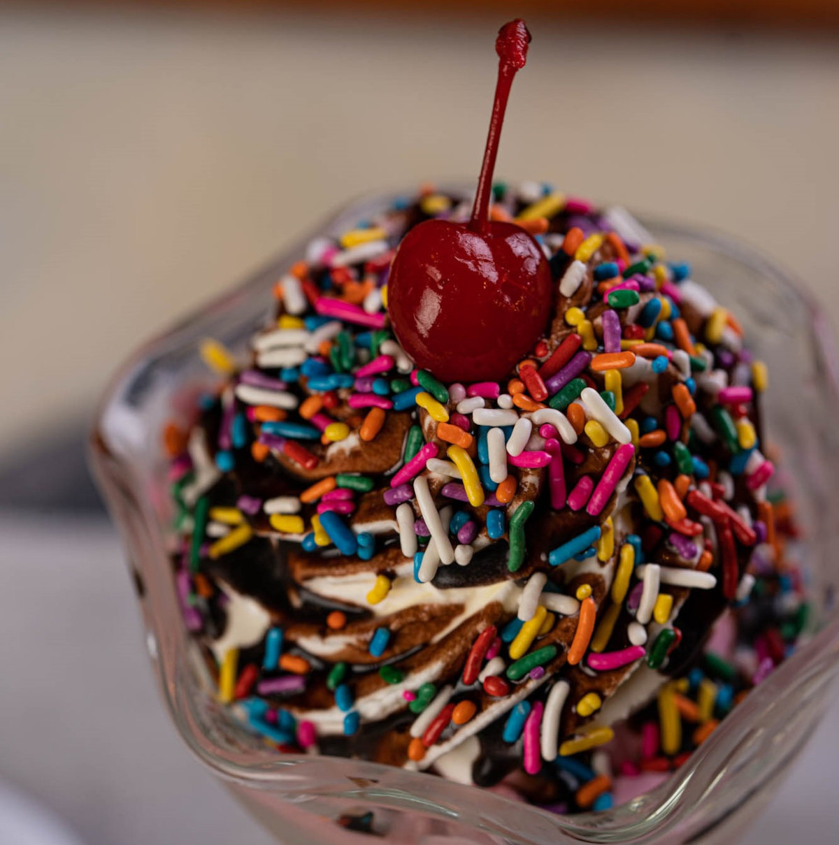 A Chocolate Ice Cream Sundae with Chocolate Syrup and Rainbow Sprinkles