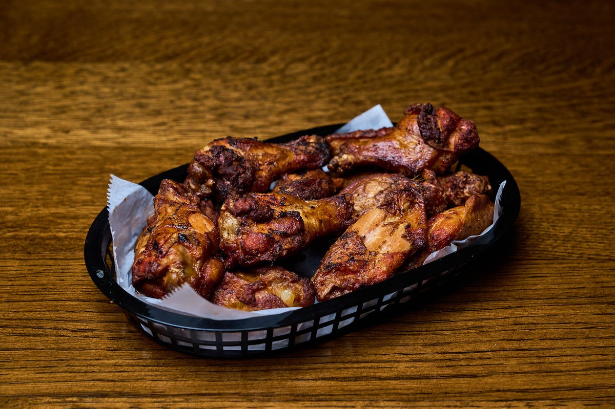 A black basket filled with crispy fried chicken wings