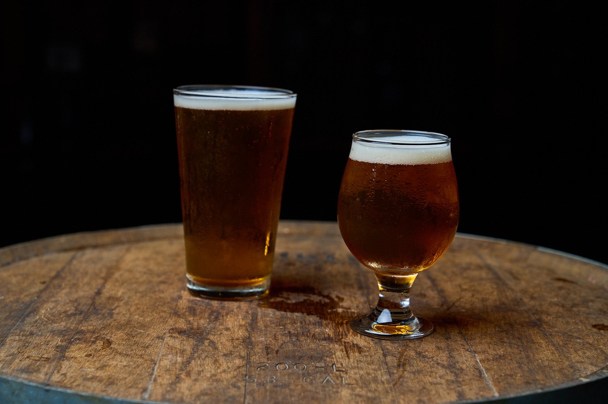 Two glasses of beer on a wooden barrel