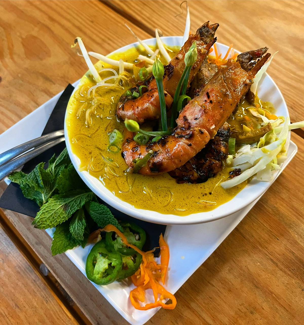 A bowl of Vietnamese noodle soup with grilled shrimp on top