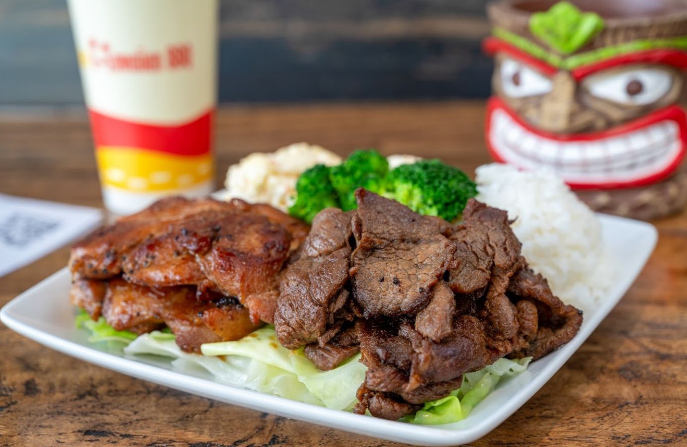 Closeup of a plate of grilled chicken and beef with some rice on the side