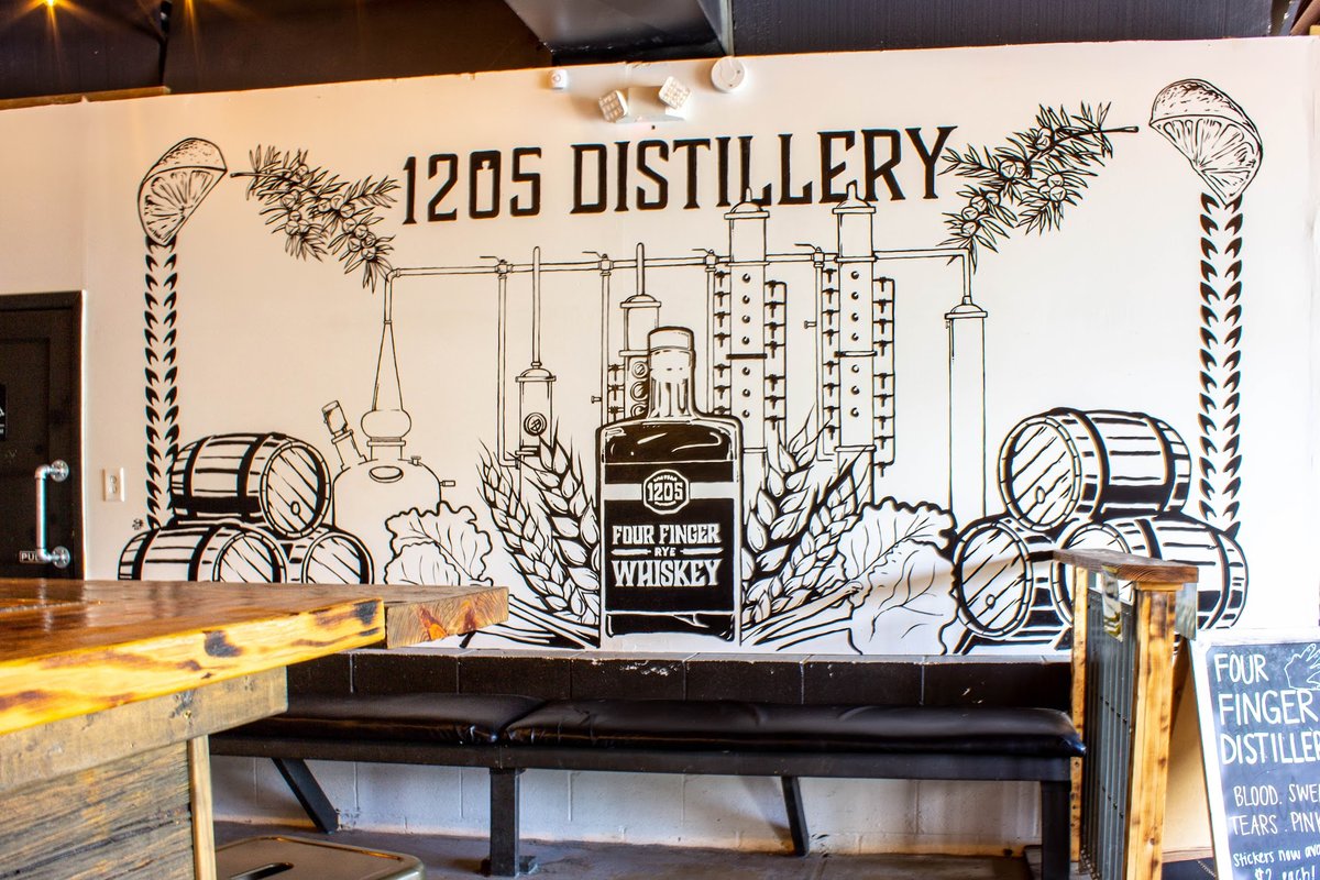 A bar with a mural of a distillery on the wall.