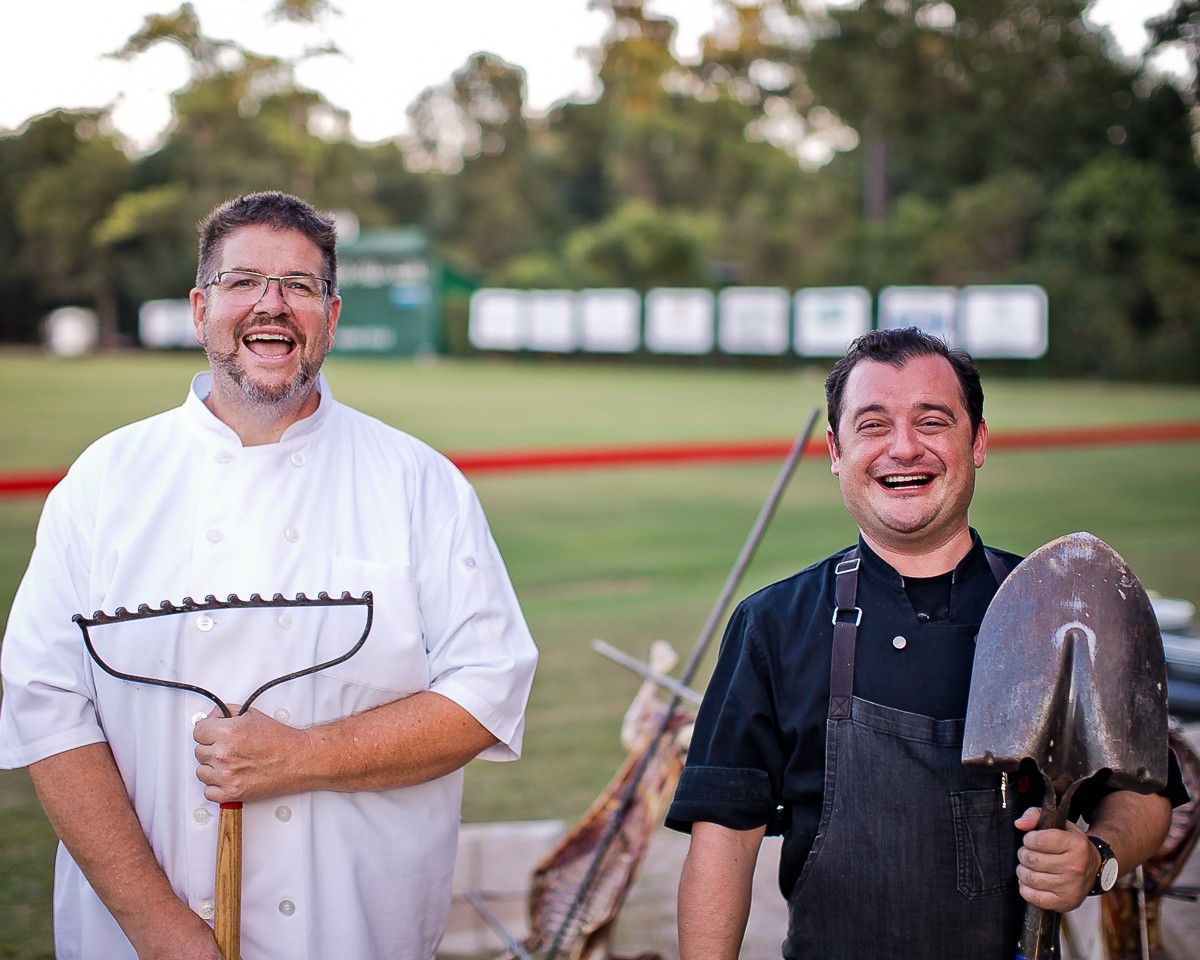 Two men in aprons holding a shovel