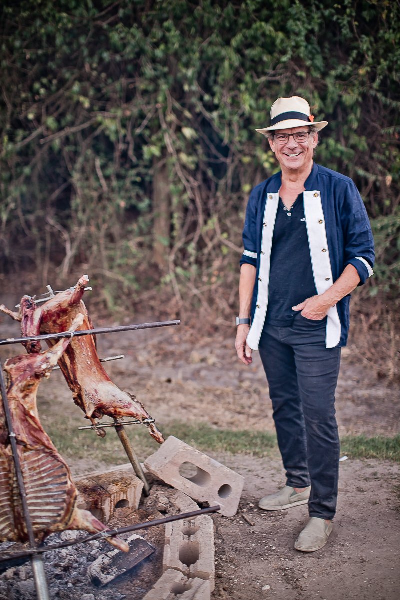 A man standing next to a grill with meat on it