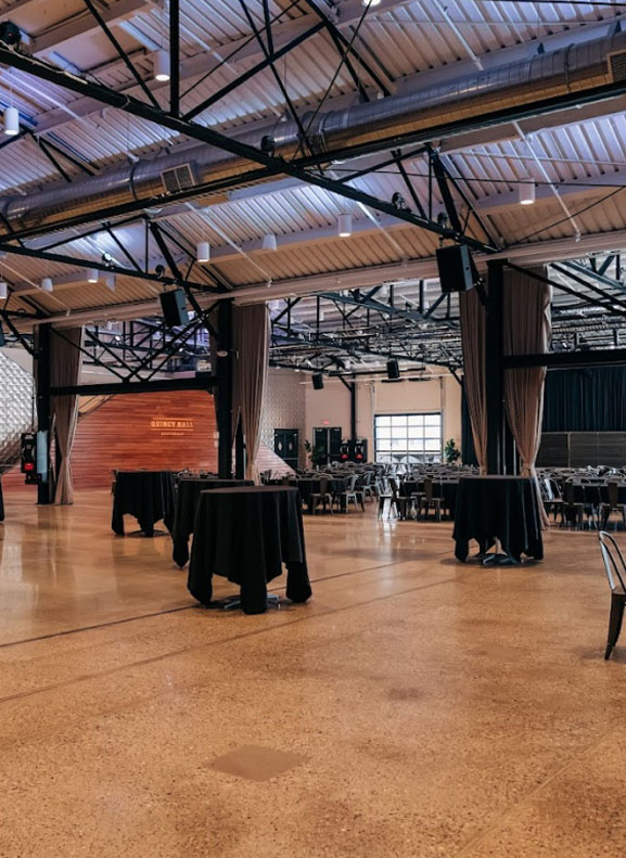 Event hall with round tables covered with black tablecloths and background stage