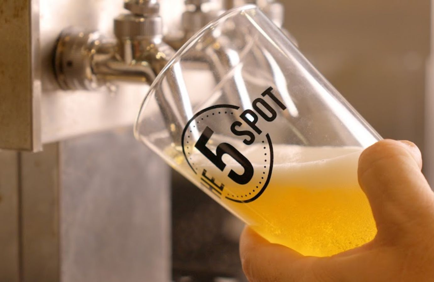 Closeup of a beer glass with spot logo being filled from a tap