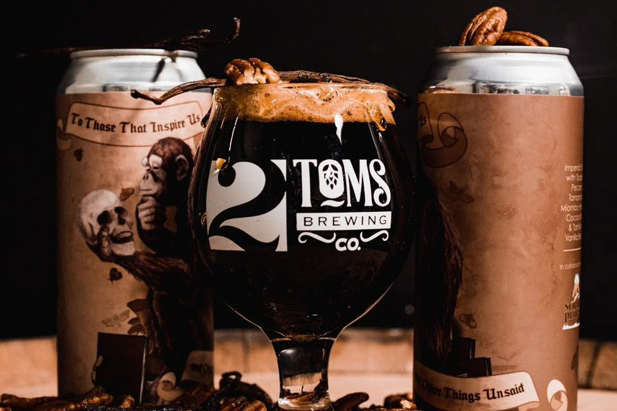 A glass and cans of dark beer, with walnuts
