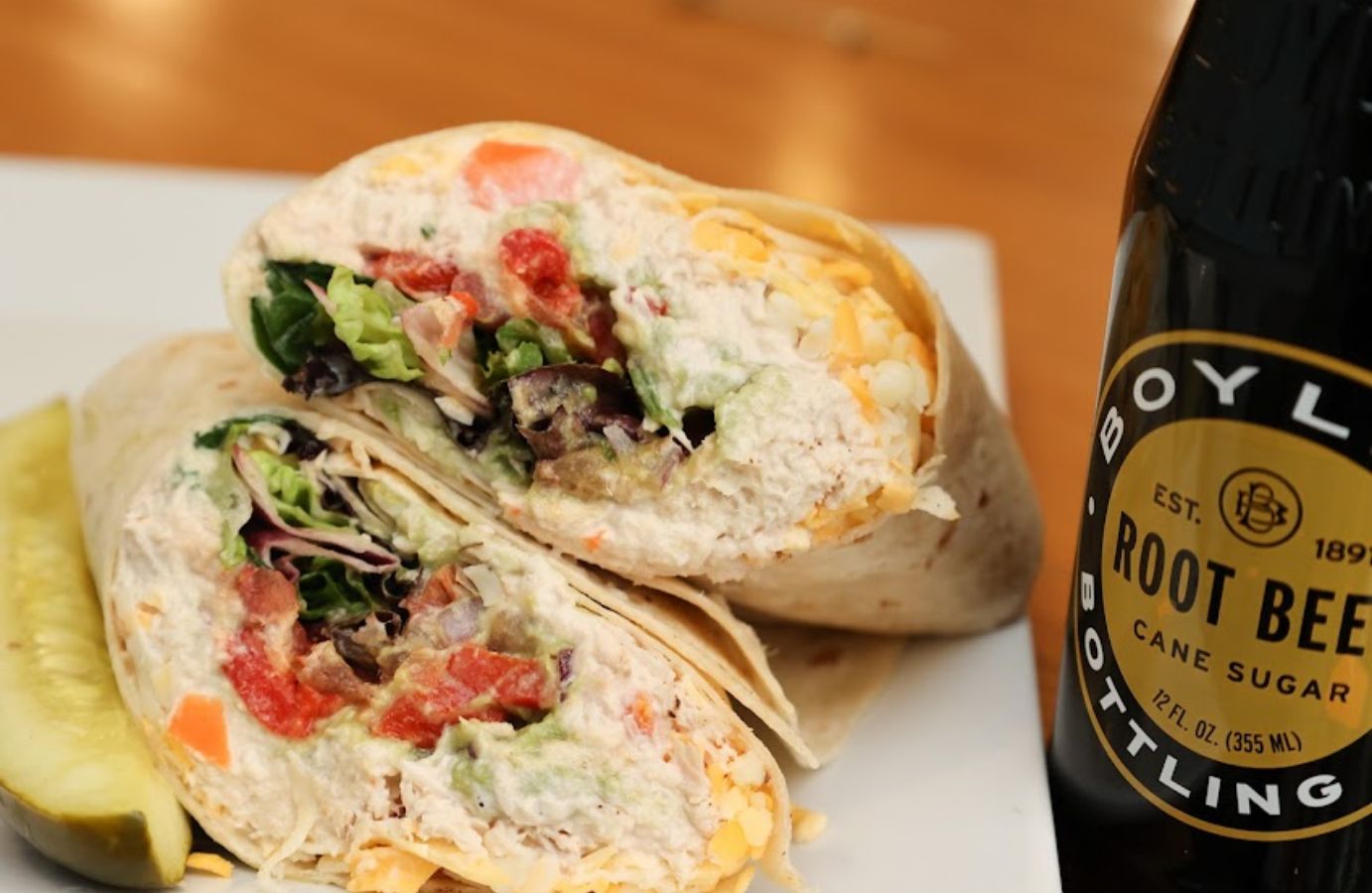 Closeup of a wrap on a plate and a bottle of root beer on the side