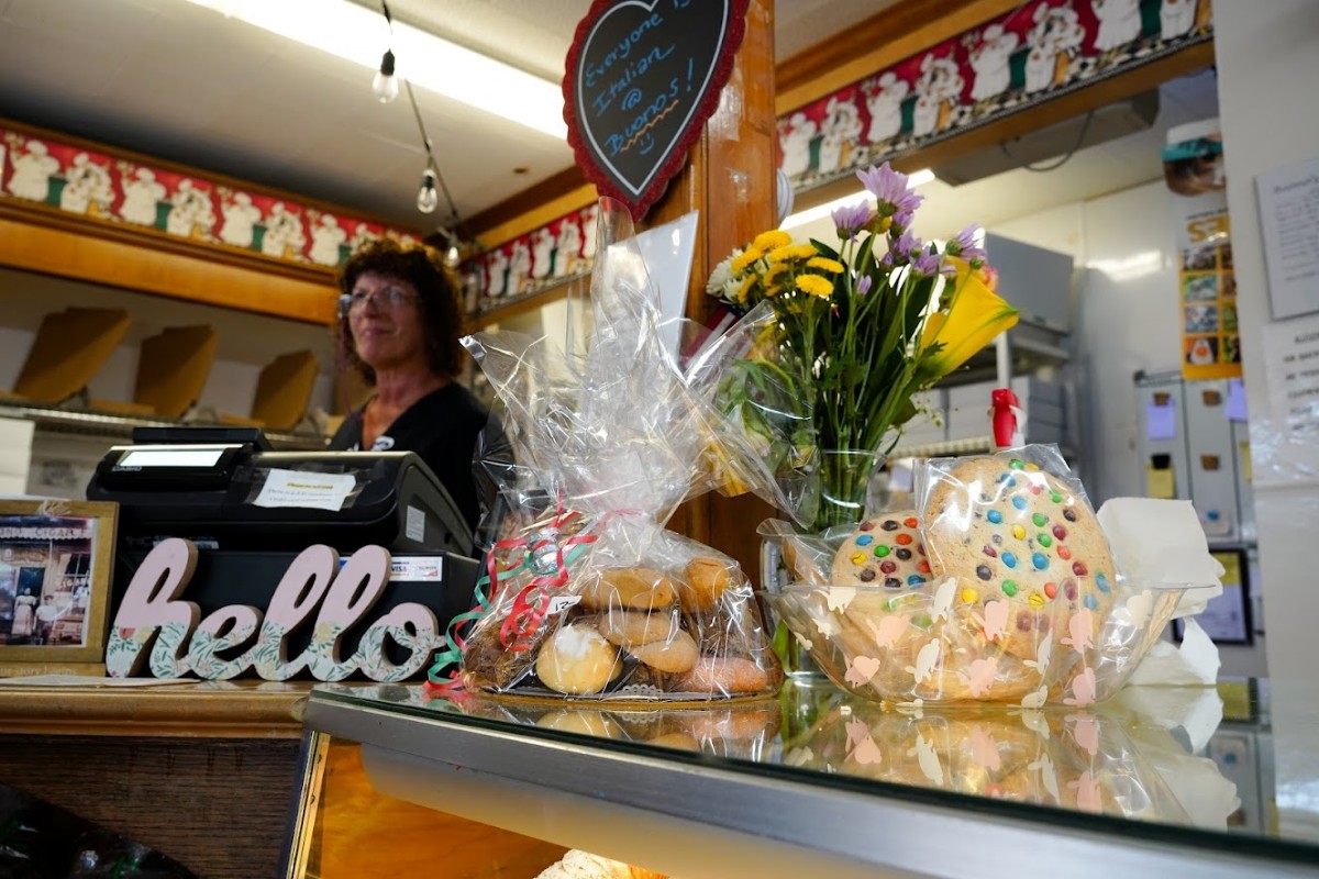 A staffer behind a counter with gift cookie packages and flowers