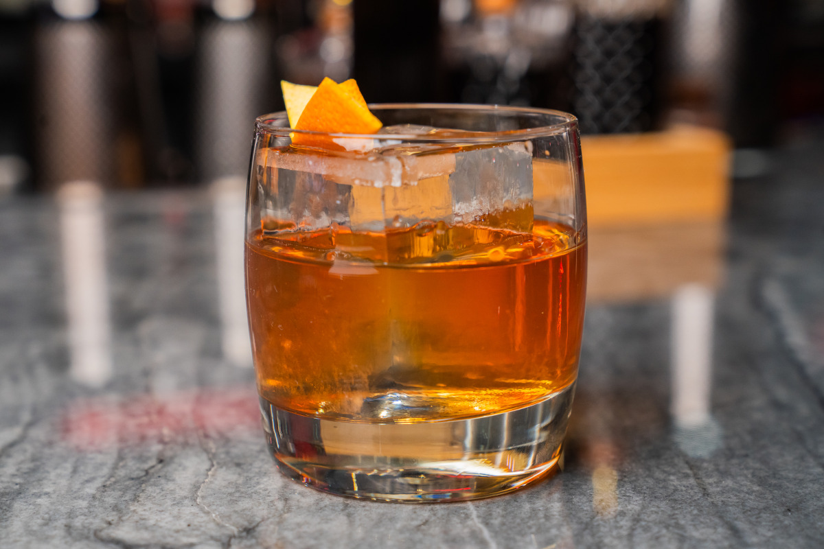 a glass of whiskey accompanied by a slice of orange placed on its surface