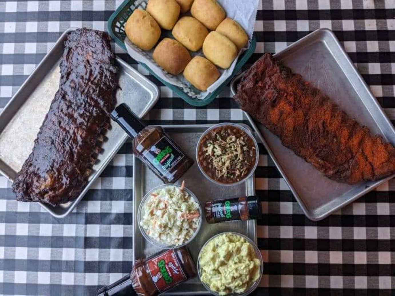 Ribs, corn bread, BBQ sauces and dips on plates.