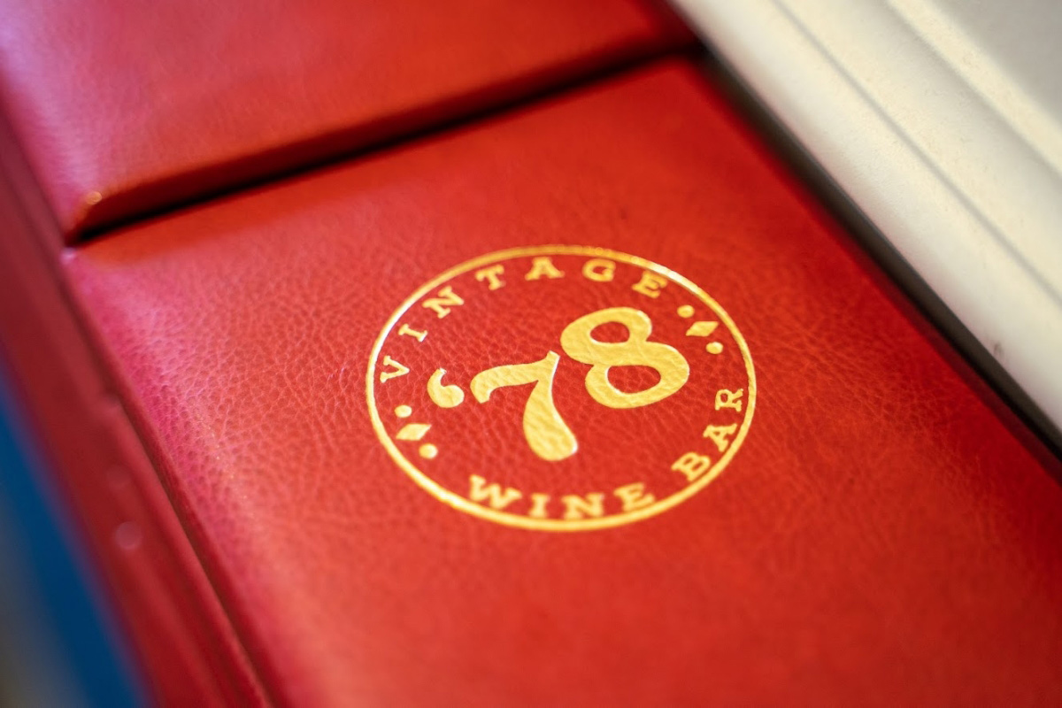 Angled view of the Vintage '78 Wine Bar logo stamped on the red leather material.