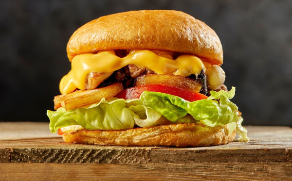 A burger with cheese and lettuce on a wooden table