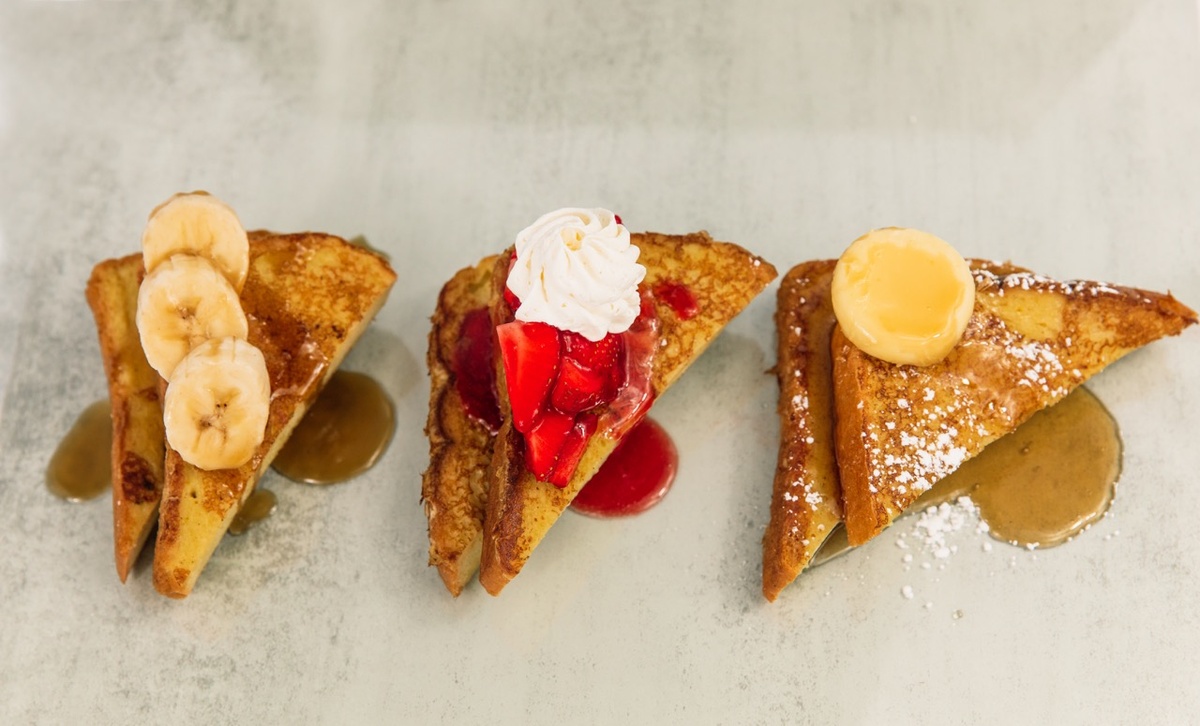 Three slices of french toast with strawberries, bananas and whipped cream.