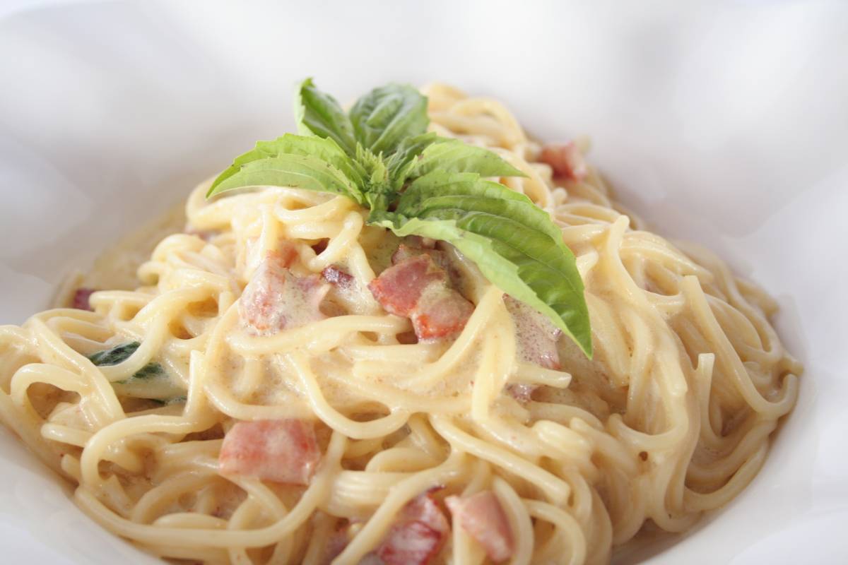 Spaghetti carbonara with bacon and fresh basil.
