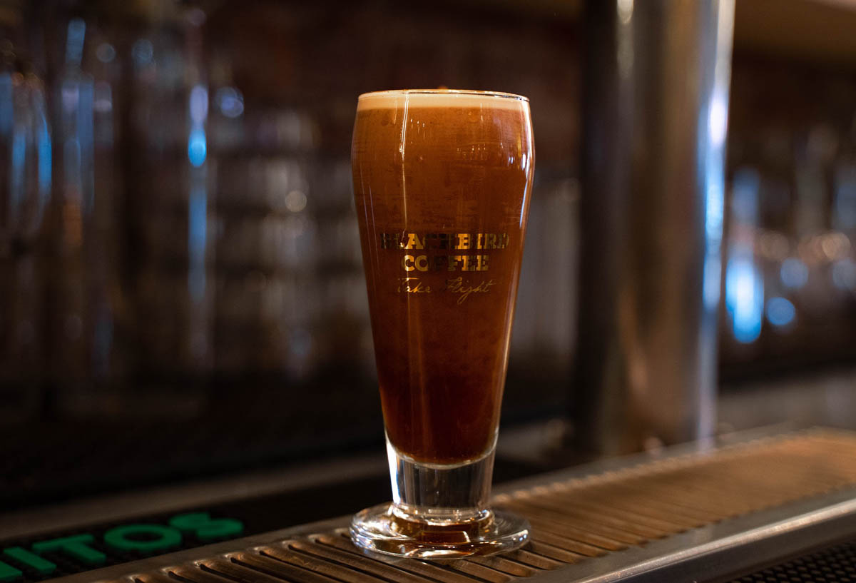 Glass of Nitro Cold Brew on bar pad