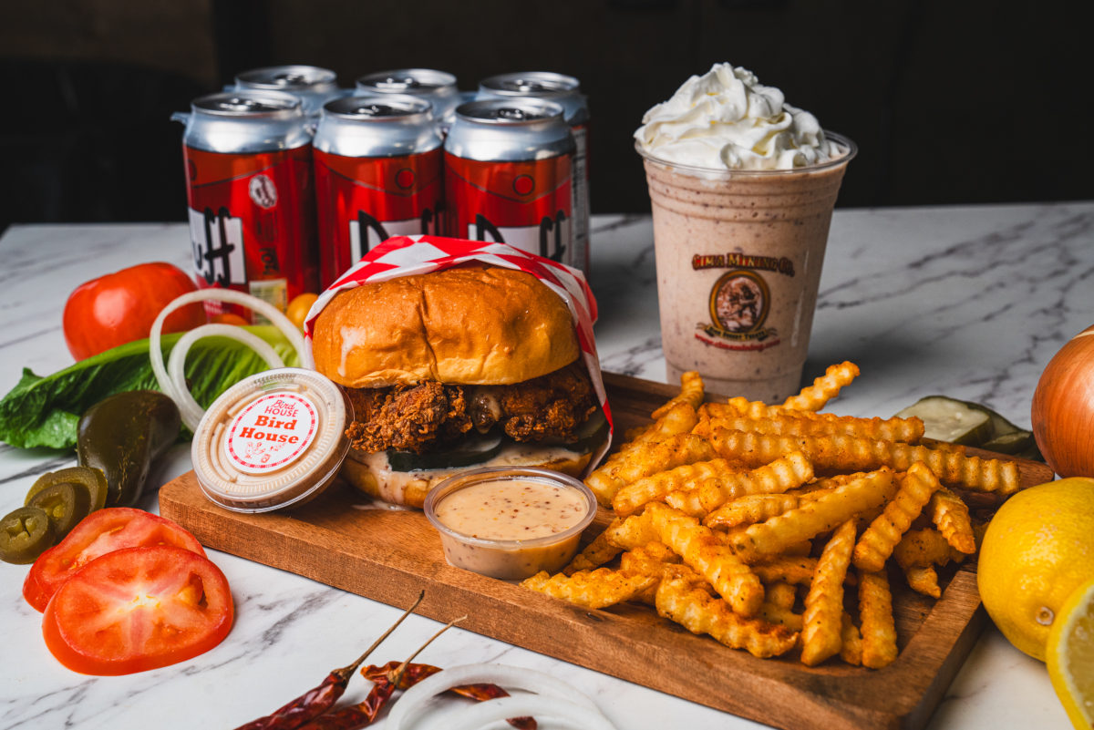 a sandwich and fries on a wooden board with drinks