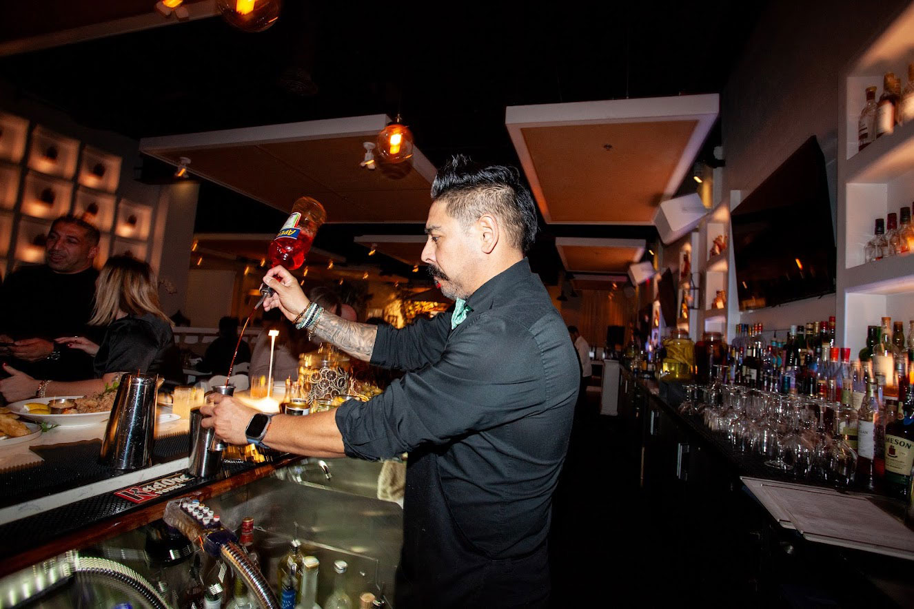 A person making a cocktail behind the bar
