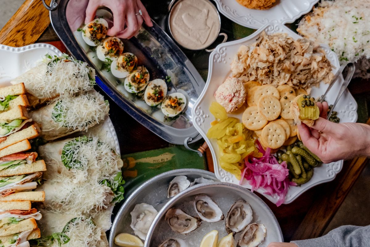 Catering spread with deviled eggs, sandwiches, wraps, oysters and a crackers platter