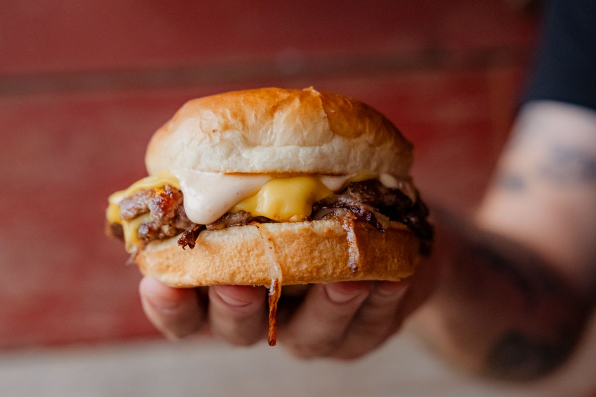 Hand holding a cheeseburger slider