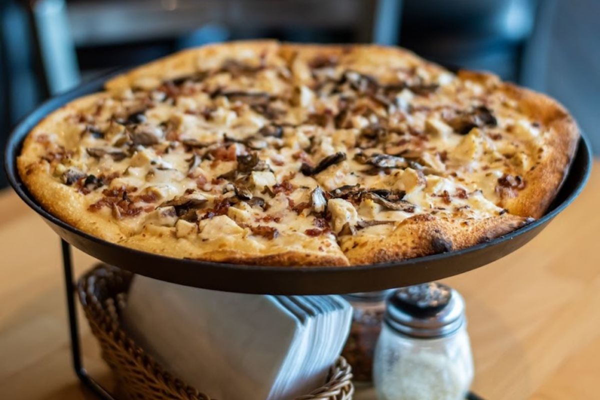 Pizza with chicken, cheese, bacon, and mushrooms