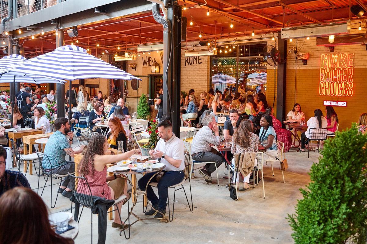  A crowded outdoor patio where guests are engaged in eating and drinking