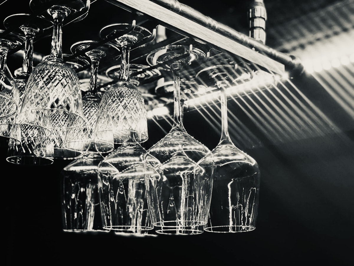 A black and white photo of wine glasses hanging from a pipe