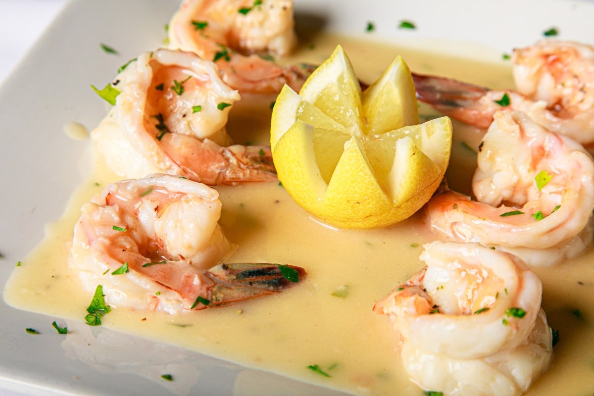 a plate of shrimp with a lemon wedge