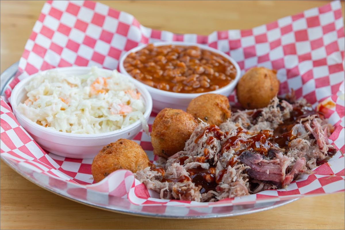 Pulled pork, with BBQ sauce, hush puppies, baked beans, and coleslaw