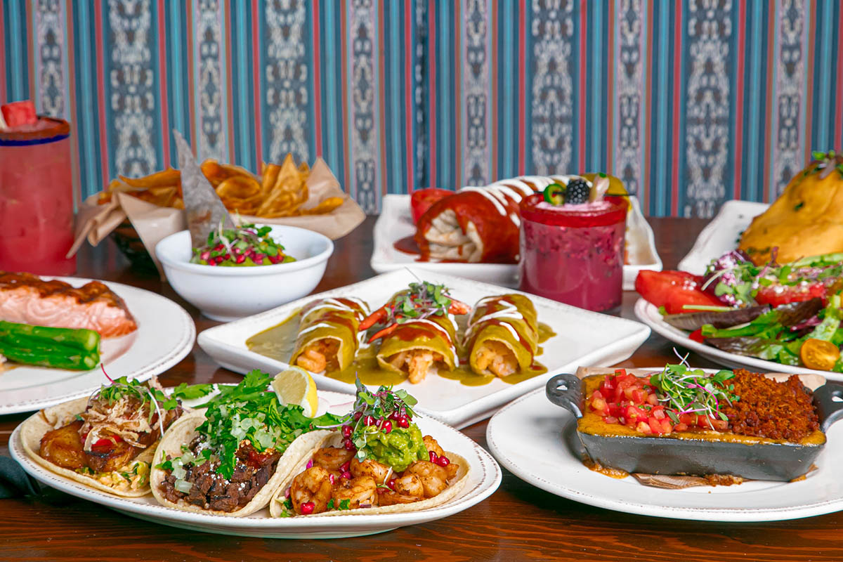 Assortment of Mexican dishes with tacos, enchiladas, chips, and more on a table