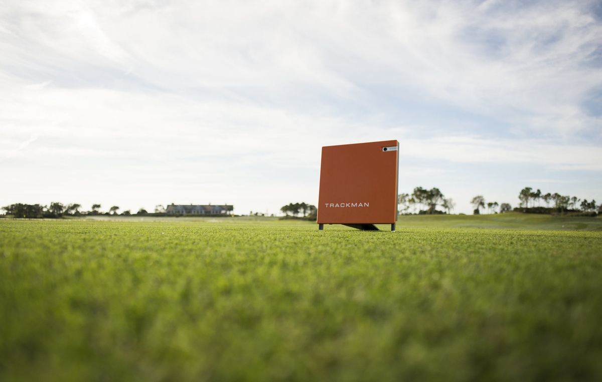 A Trackman radar unit on a golf course with the clubhouse in the distance.