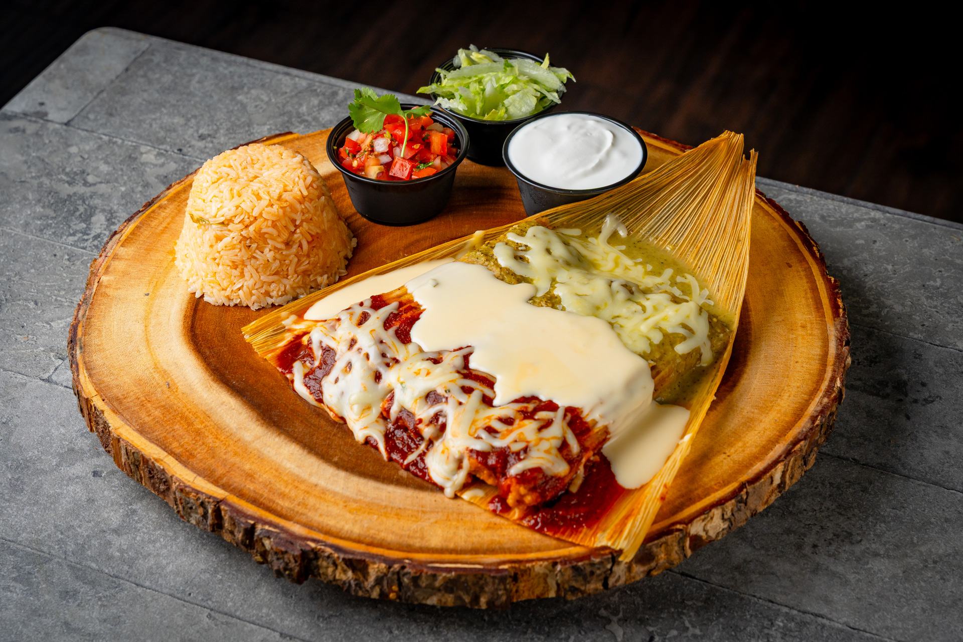Two cheese-covered enchiladas with red and green sauces