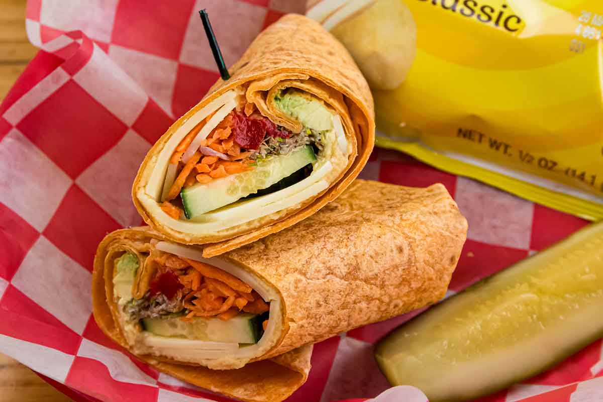 A healthy vegetable wrap with a side of pickle, placed on a table.