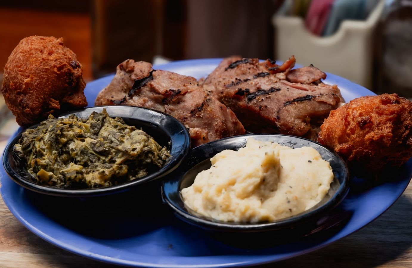 Front view of a plate with char-grilled pork shanks with mashed potatoes and vegetables on the side