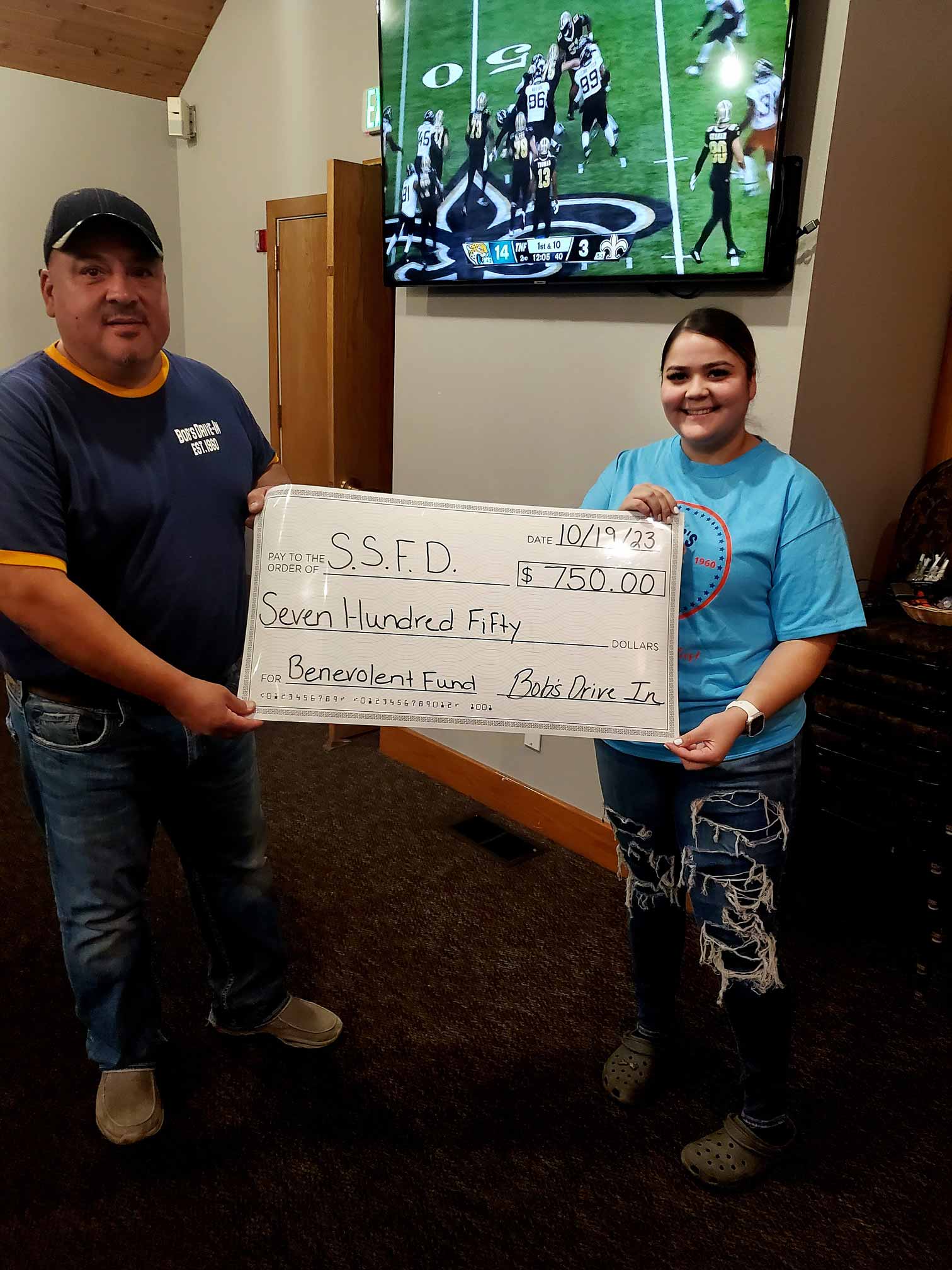 Man and girl holding charity check