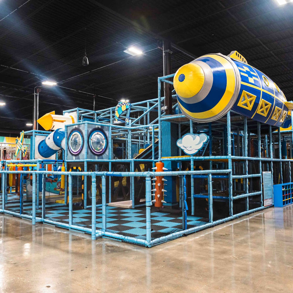 A large indoor play area with a blue and yellow play structure.