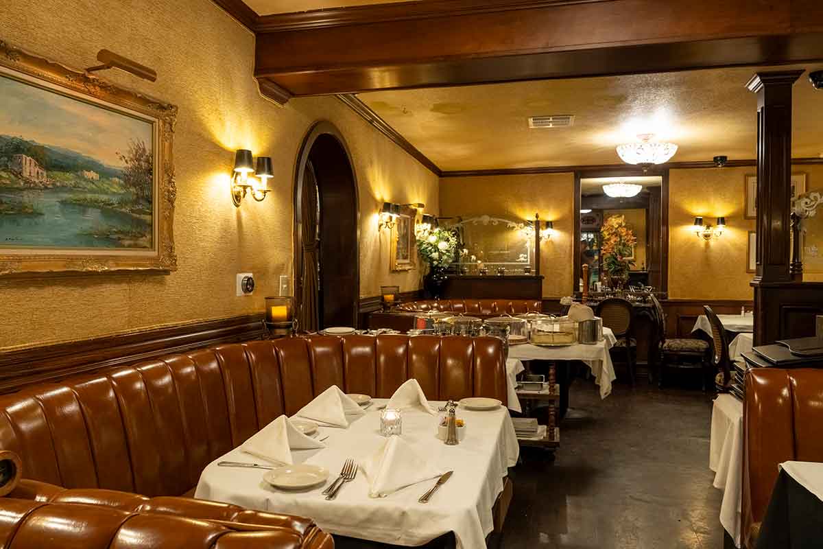 An upscale restaurant with brown leather booths, white tablecloths, and warm lighting.