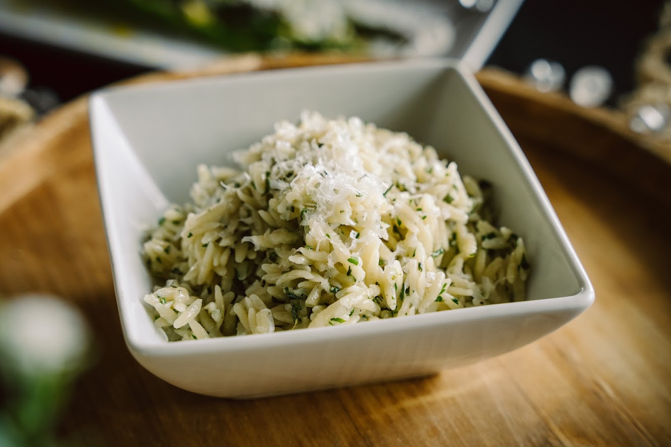 A bowl of rice and parmesan cheese on a wooden table.