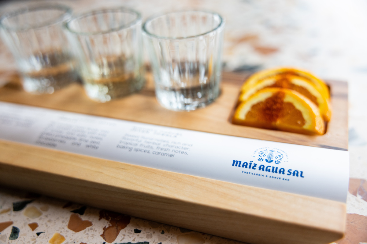wooden tray with three glasses and a slice of orange