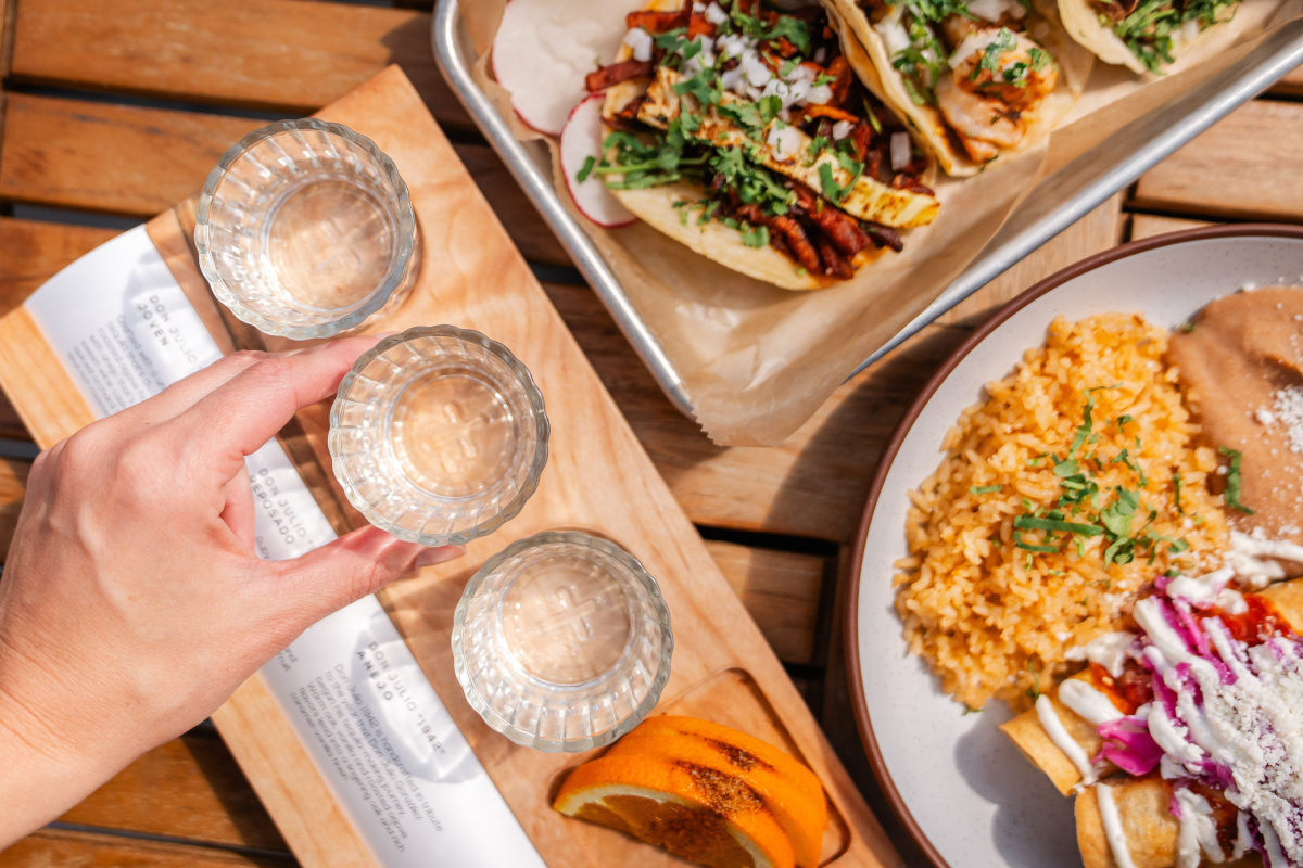 person holding a plate of food and three glasses