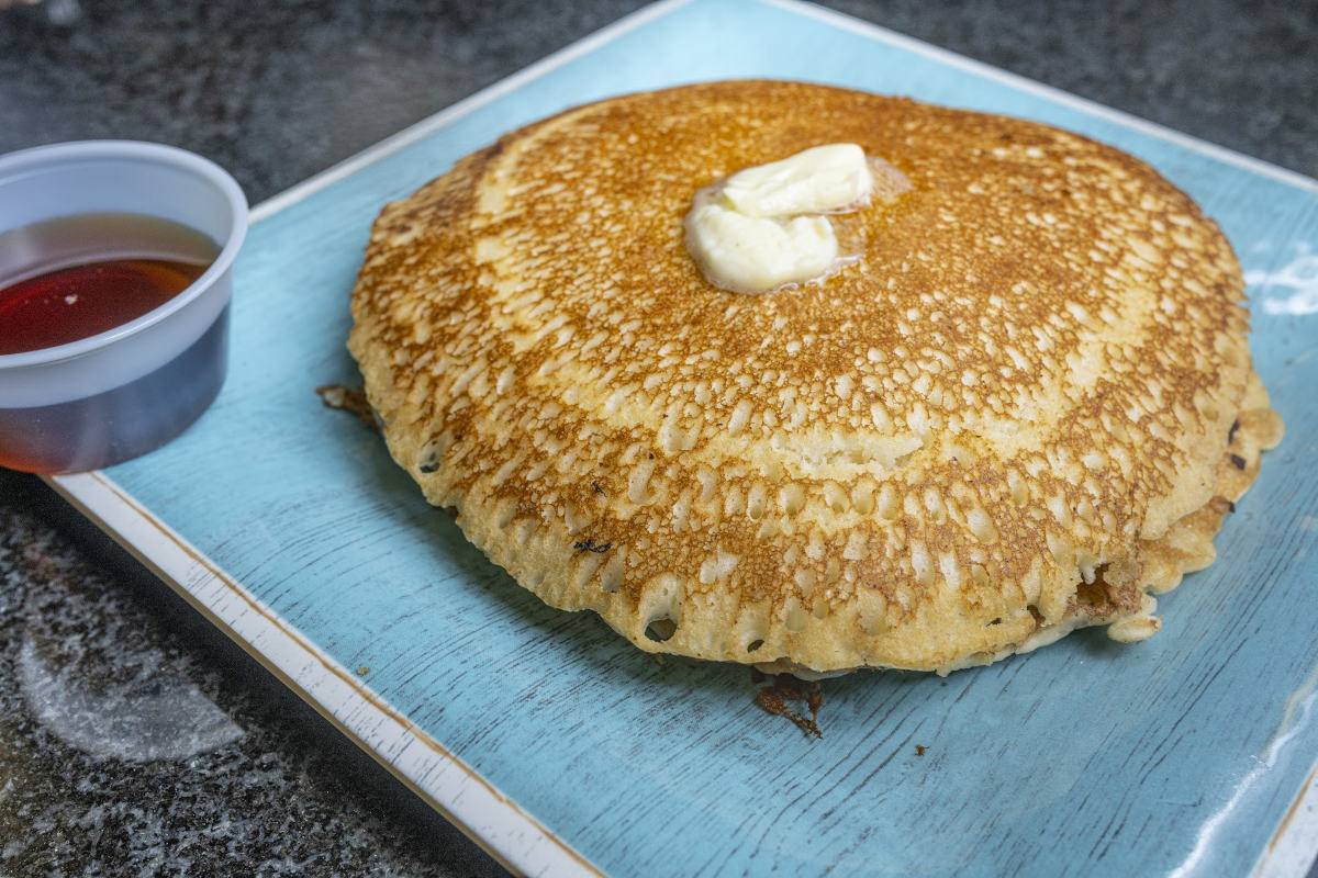 A golden pancake on a plate topped with melting butter