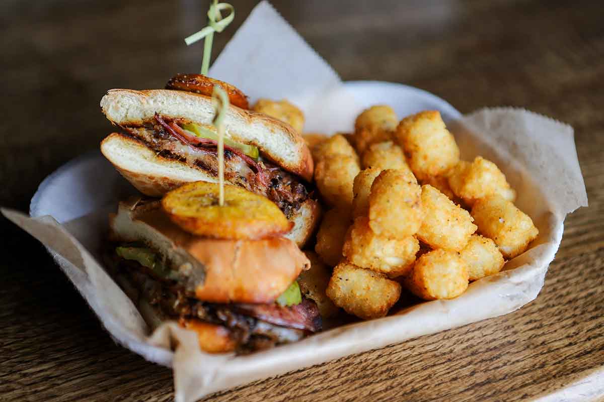 Smoked pork sandwich, with Canadian bacon, pickles,  Swiss, mustard, and tots