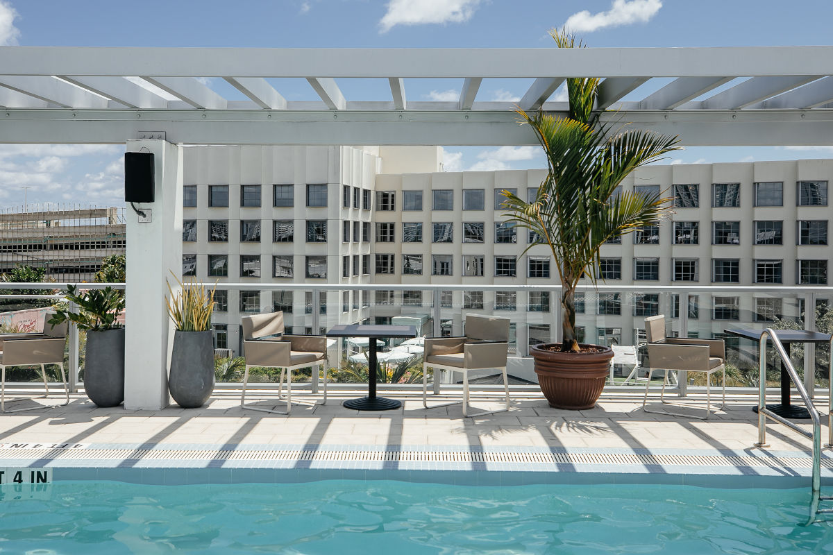 Pool surrounded by seating and a pergola for shade.