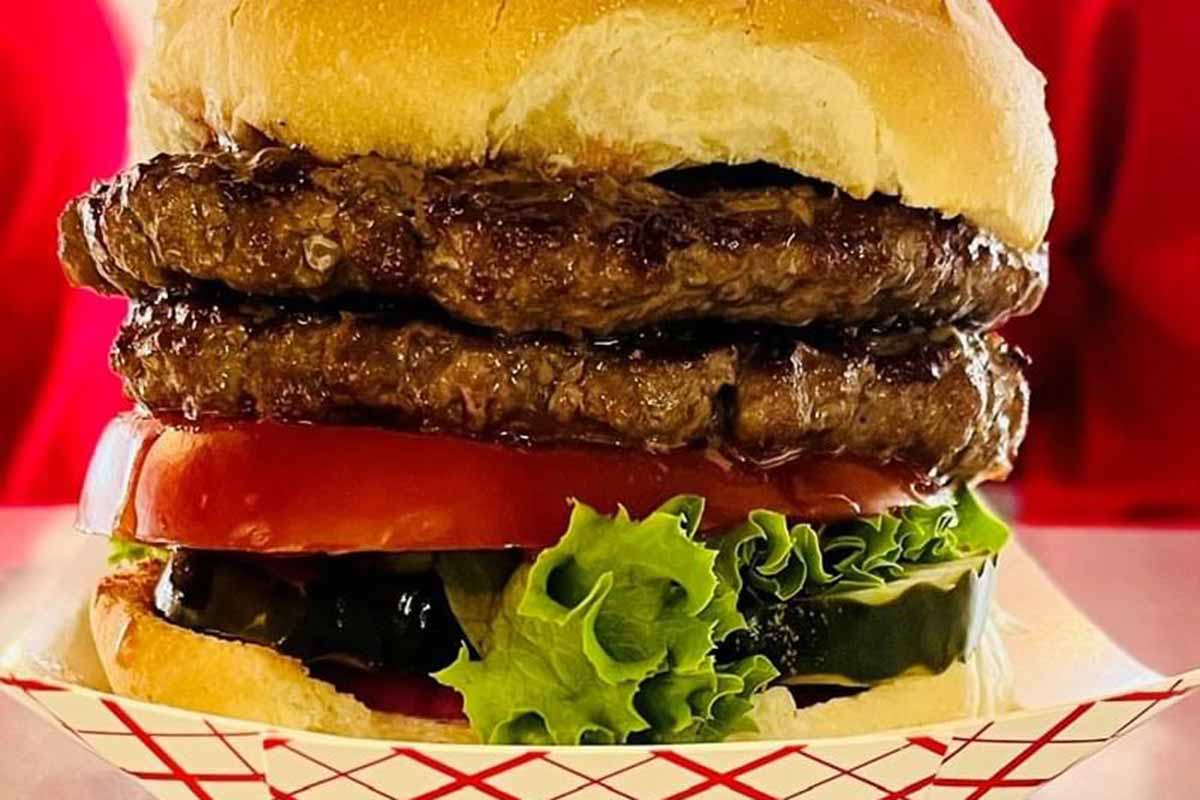 A hamburger with tomato, lettuce, onion and pickle