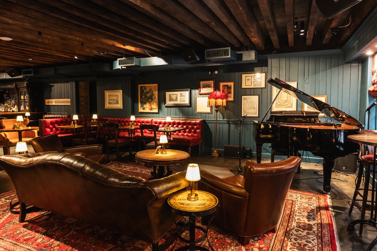 Elegant jazz club interior with red booths, a grand piano, leather couches.
