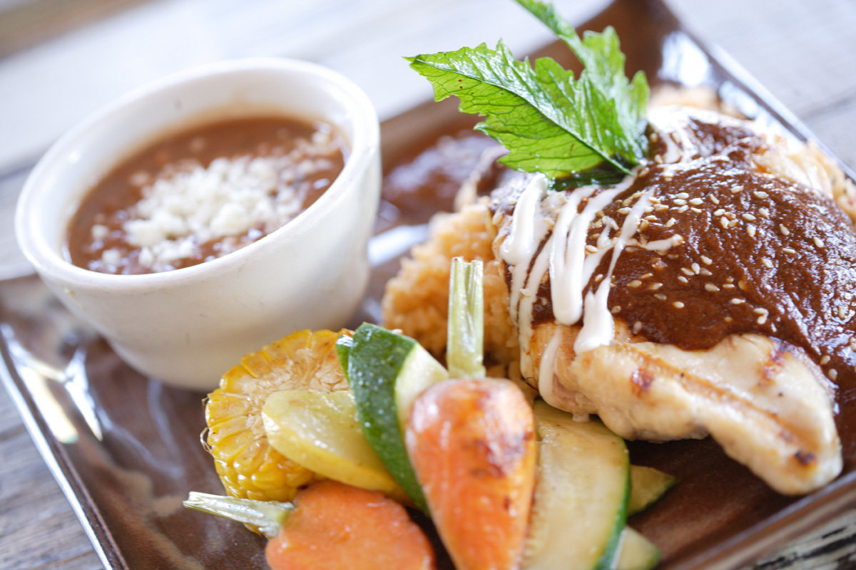 Folded stuffed pastry topped with sesame sauce, served with dip and veggies