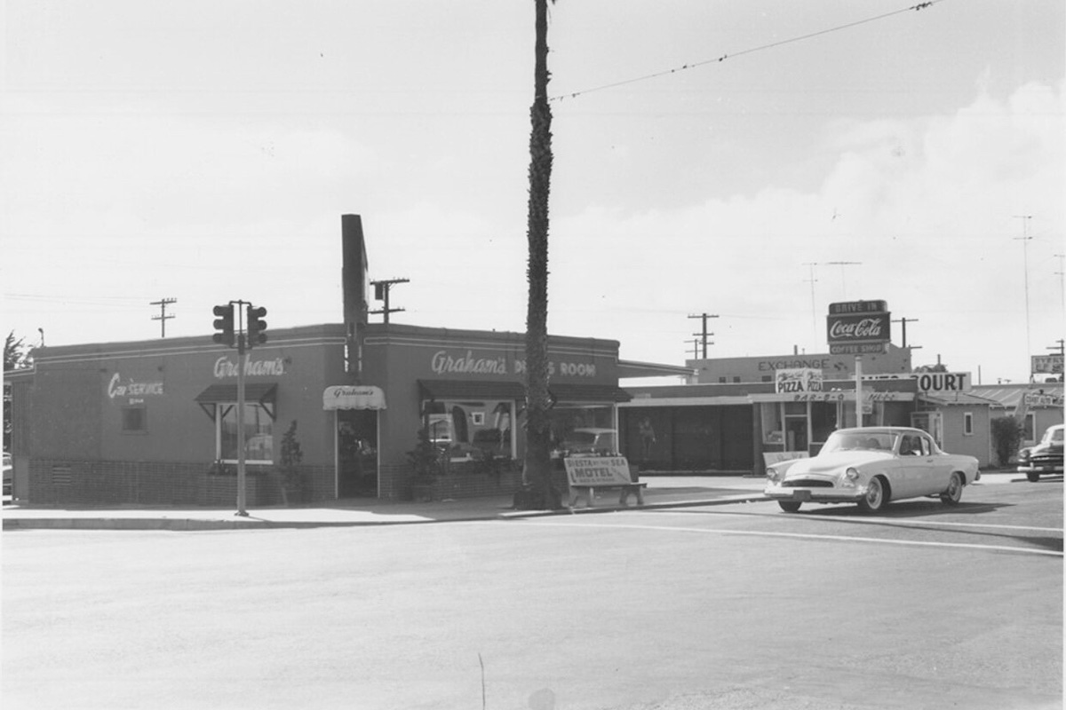 vintage gas station with a parked car in the foreground.