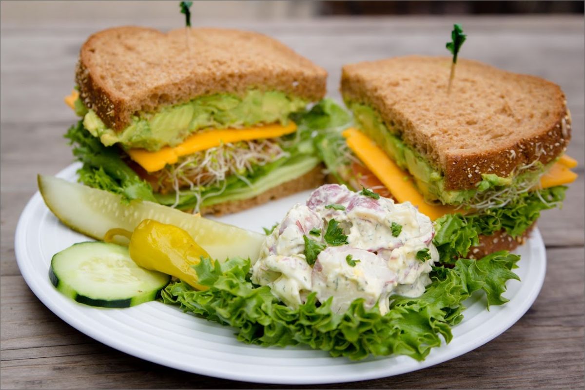 Sandwich with avocado, lettuce, tomato, sprouts, and cheese